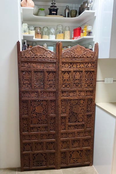 Bali screens propped up in the kitchen space where they will be installed as a pantry door