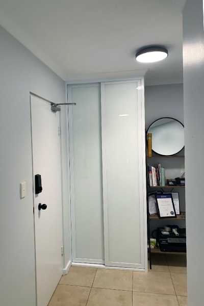 Updated room showcasing a cupboard with white glass sliding doors and shaker-inspired white frames