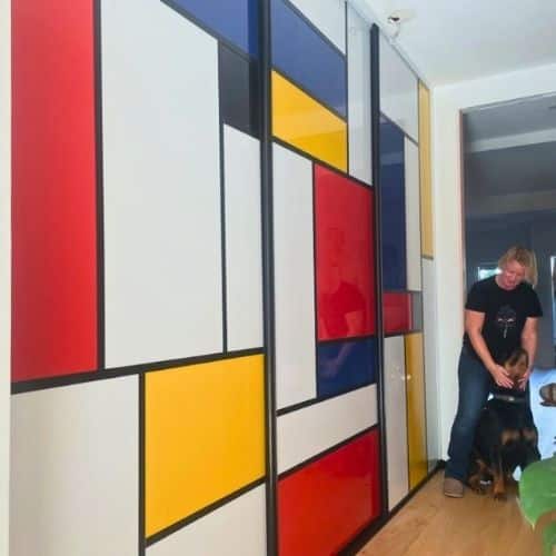 Colourful sliding doors in Mondrian style with red, yellow, blue and white panels framed in black, in a hallway