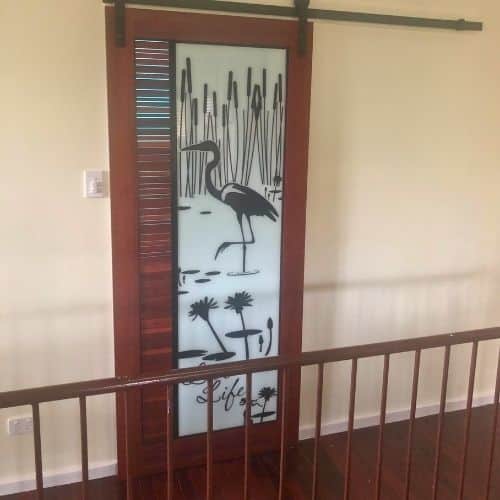 Timber-framed sliding door with printed artwork of a billabong and a jabiru.