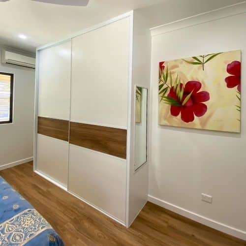Bedroom sliding wardrobe doors with a horizontal timber strip across white panels, matching timber flooring